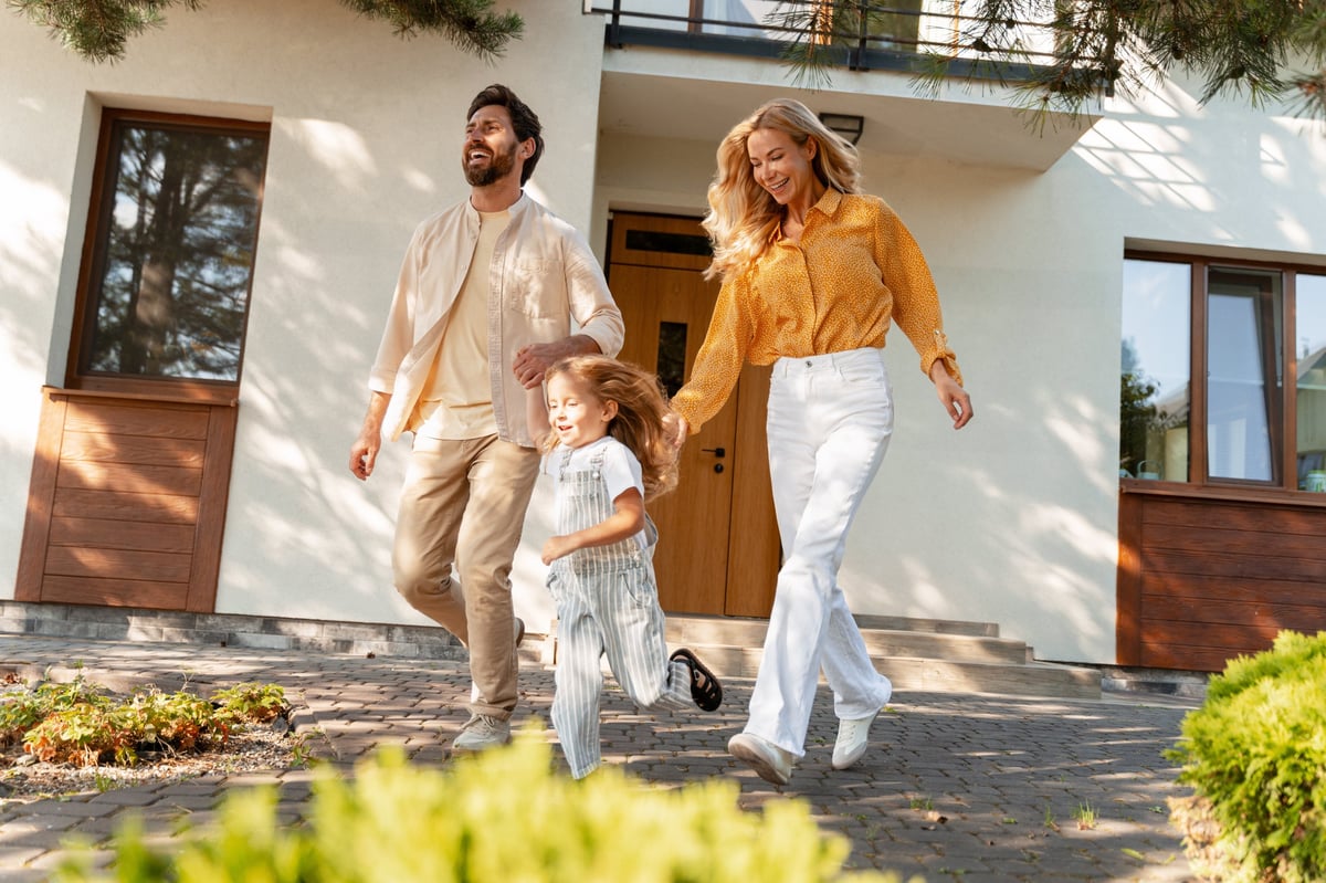 Cheerful family running toward their home on a sunny day, representing a positive next chapter and moving forward